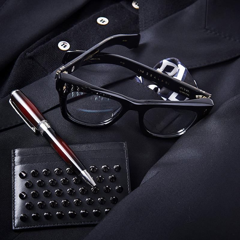 10mm厚のアセテート生地から削り出したボリューム感満点の「ディラン」は、名前の通りボブ・ディランへのオマージュモデル。巷の黒セルにはない存在感と照りが、オトナの目元にミステリアスなオーラを纏わせます。スタッズがアイコニックなルブタンのカードケースで名刺交換し、打ち合わせでは唯一ボルドーに彩られたデュポンのペンを走らせれば、間違いなくヤリ手に見せることができるでしょう。メガネは上と同じ、ボールペン9万円/エス・テー・デュポン(エス・テー・デュポン銀座ブティック)、カードケース3万7000円/クリスチャン ルブタン(クリスチャン ルブタン ジャパン)