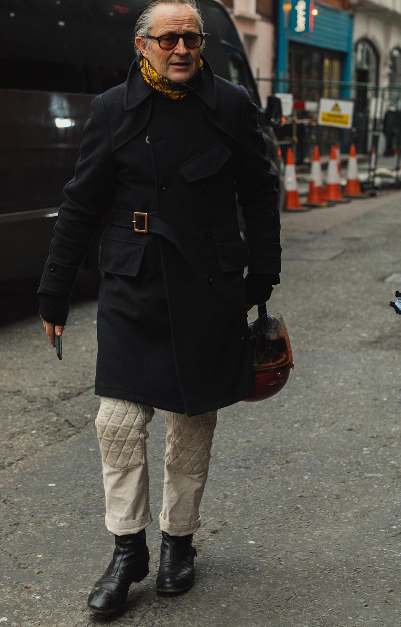 キュッと締めたベルテッドコートがお似合いの御仁。オールバックにしたロマンスグレーを艶めかせているのは、首元に巻かれたイエローのスカーフ。柄が黒なので、着こなしに統一感も生まれています。