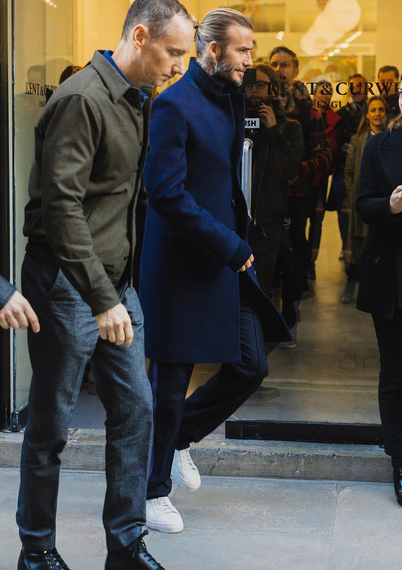 オーセンティックなネイビーのチェスターコートの襟を少し立てて、コレクションに向かうのは、デビッド・ベッカムさん。紺のウールパンツにはラインが入っていますが、足元の白スニが軽快な感じを引き立てています。