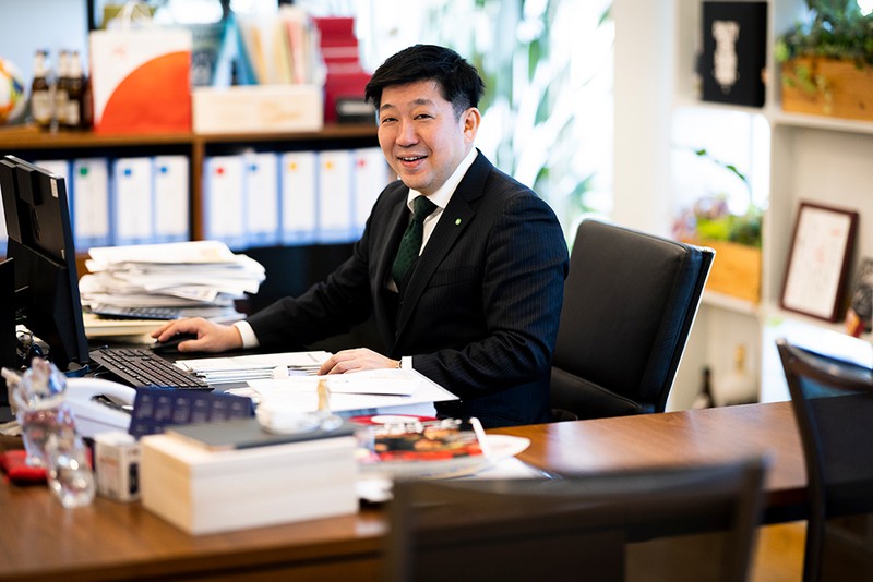 西原商会 デスクに座ってもらい、パチリ。「その書類の山の中には日本サッカー協会の会計に関するものもある」と一将社長。鹿児島県のサッカー協会の会長を務めていたことがきっかけで、日本サッカーの財政状態を把握・管理することになったそう。