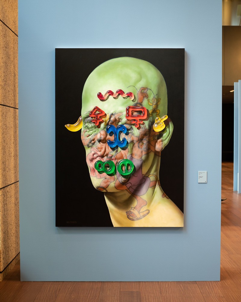 ▲ アメリカ出身のアーティスト、クリスチャン・レックス・ヴァン・ミネン（1980〜）による「アイドル」（2021）。一見して、驚いたのはその確かな画力。ですが、不思議なモチーフが散りばめられた絵でもあります。リアルな質感の皮膚の上にはエスニックな男性のタトゥーが描かれ、置かれているのはカラフルなグミ。肌の色がグリーンなのも意味がありそうです。