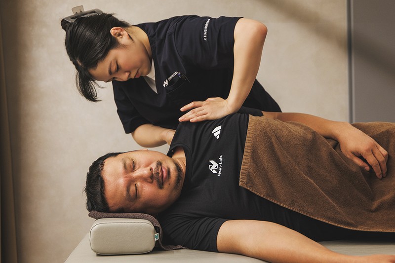 問診を経て、施術スタート。基本的に最初は鍼灸接骨院で全身を整えます。カラダの歪みや痛みにピンポイントでアプローチし、その後、ピラティスで姿勢の矯正やパフォーマンス向上のためのメニューをする流れになります。「鍼灸接骨院」の鍼灸師・橋本双葉さんが、渡辺のカラダ状態をしっかりチェック。