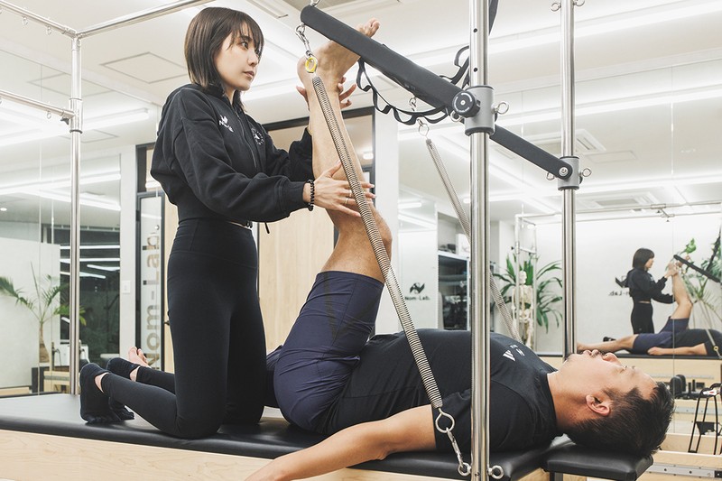 ピラティススタート。橋本さんからの申し送りを基に、MIOさんがカラダの状態に合ったメニューを考えます。まず、「キャデラック」というマシンを使い、下半身のアライメントを整えることで、足裏の使い方や正しい体幹の安定性を引き出していきます。普段なかなか伸ばすことがないので、イタ気持ちいい～。
